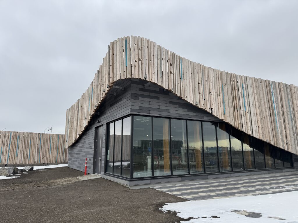 completed water reservoir with floor to ceiling windows, grey brick and rows of natural wood framing the structure