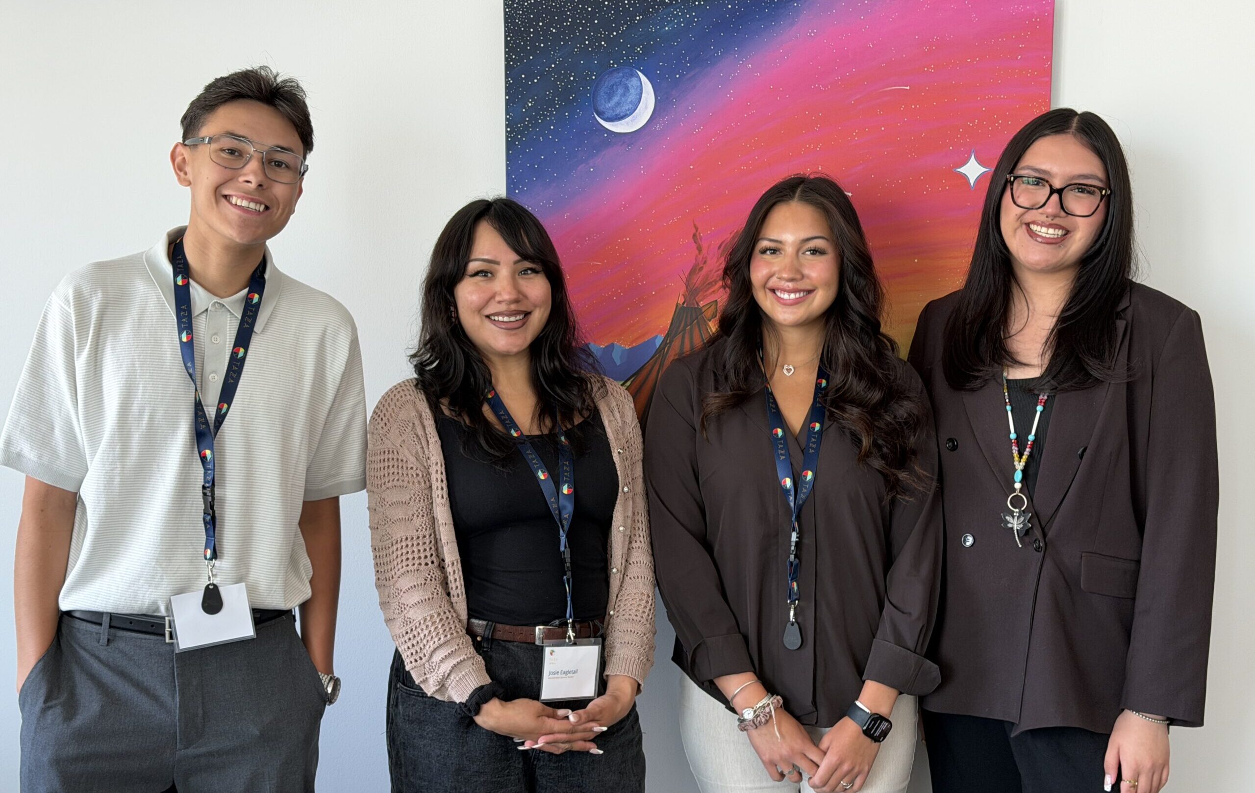 Four people in office attire standing in front of a brightly coloured painting