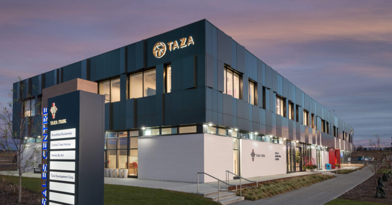 Taza Park Sales & Marketing Centre exterior with green grass and sunset background.
