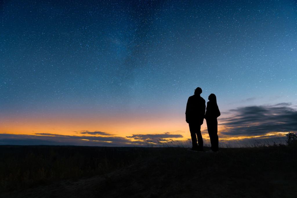 Couple gazing at the starry skies as the sun sets