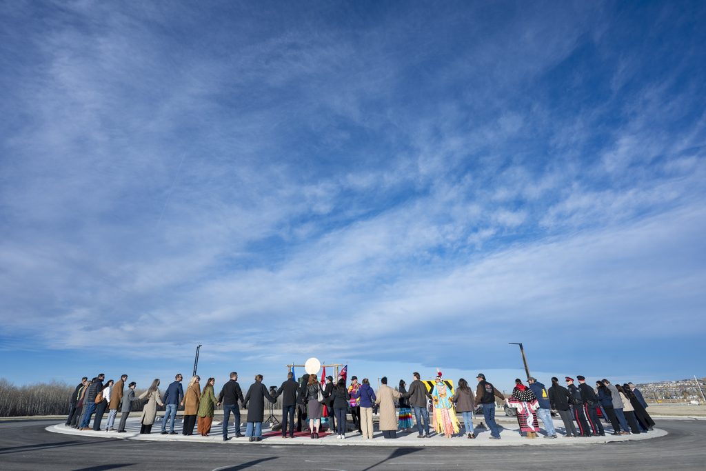 People holding hands for a round dance around a large traffic circle.
