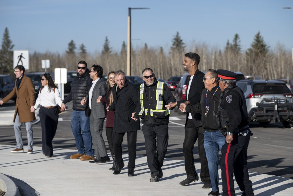 People laughing and holding hands while they round dance around a traffic circle.